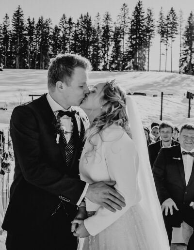 Brautpaar in ihrem warmen Outfit für die Winterhochzeit in den Bergen bei der Trauung