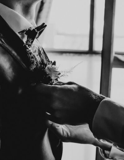 Der Trauzeuge hilft dem Bräutigam beim Anbringen der Boutonniere am Hochzeitstag in den Bergen