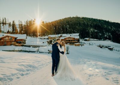 Brautpaar bei ihrer Winterhochzeit in den Bergen im Sonnenuntergang