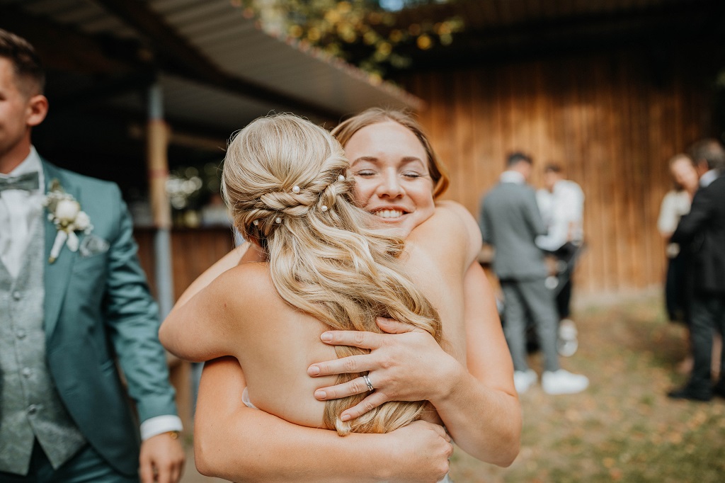 Umarmung zwischen Hochzeitsplaner und Braut auf ihrer Berghochzeit