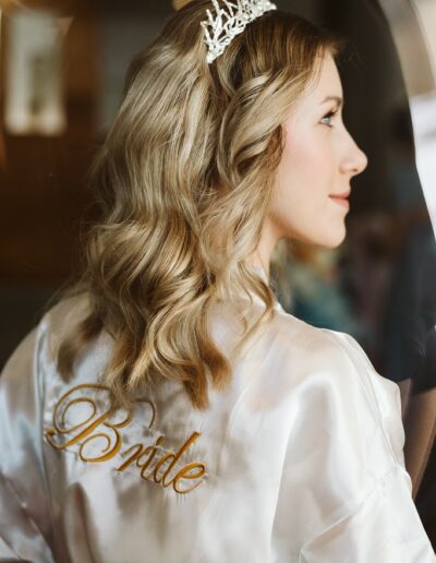 Fertig gestylte Braut mit Krone und Morgenmantel an ihrem Hochzeitstag in den Bergen