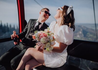 Lachendes Brautpaar in der Gondel in den Bergen auf dem Weg zu ihrer Berghochzeit