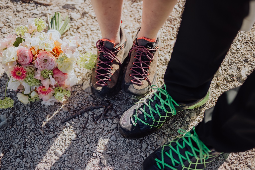 Bridal couple with hiking boots for the hike to their wedding ceremony on the mountain top in Austria
