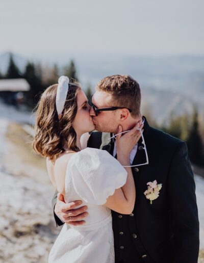 Kissing bride and groom on the Zwölferhorn at their mountain wedding