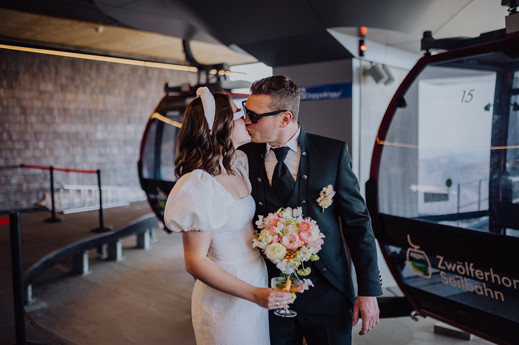 Kissing bride and groom shortly before their arrival at their mountain wedding at the gondola station