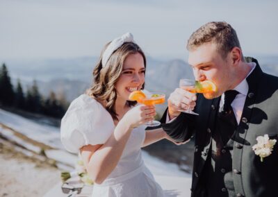 Glückliches Brautpaar trinkt Aperol bei ihrer Hochzeit in den Bergen