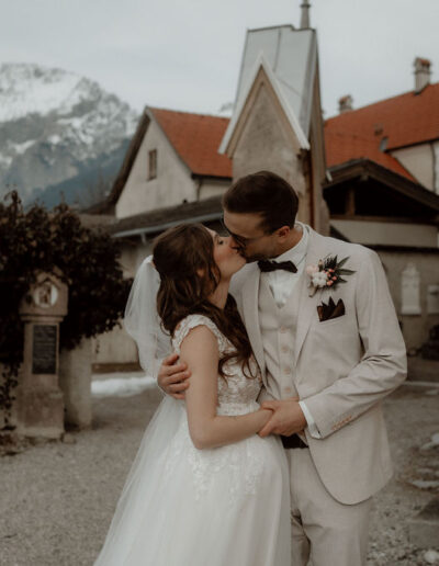 Brautpaar küssend vor der Kirche bei ihrer Winterhochzeit mit Wedding Planner